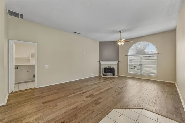 an empty room with wooden floor cabinet and fireplace