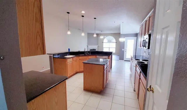 a kitchen with granite countertop a sink a counter top space stainless steel appliances and cabinets