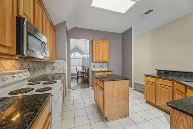 a kitchen with stainless steel appliances granite countertop a stove a sink and a microwave