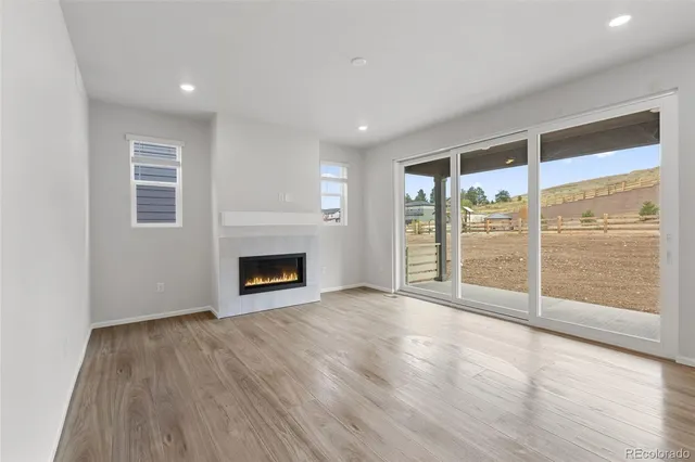 an empty room with wooden floor fireplace and windows