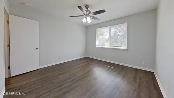 an empty room with wooden floor and windows