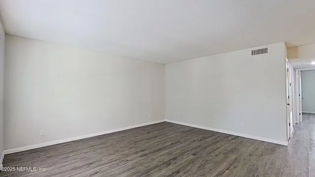 a view of an empty room with window and wooden floor