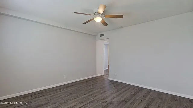 an empty room with wooden floor and a ceiling fan