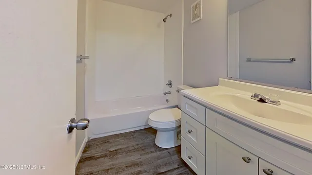 an empty room with wooden floor ceiling fan and windows