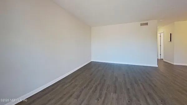 a view of an empty room with wooden floor