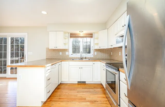 a large white kitchen with granite countertop a sink and dishwasher a stove top oven with wooden floor