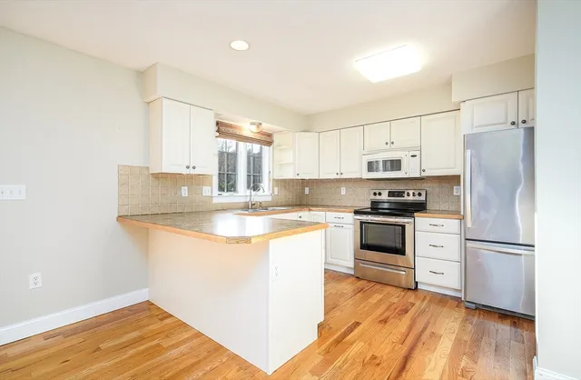 a kitchen with stainless steel appliances granite countertop a refrigerator a stove and a sink