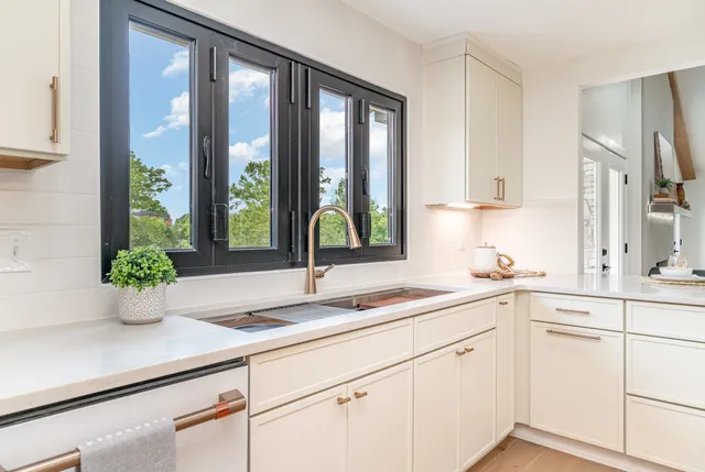 a kitchen with stainless steel appliances white cabinets and a large window