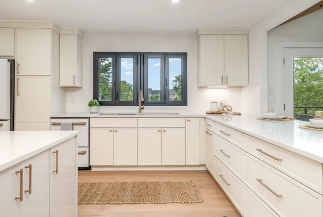 a kitchen with white cabinets a sink a stove and a window