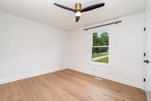 an empty room with a window and wooden floor
