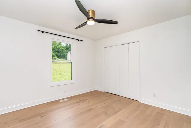 an empty room with a window and a ceiling fan