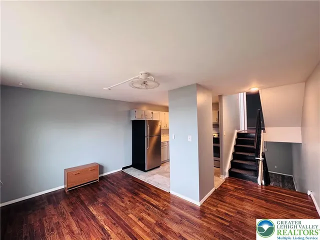 a view of an empty room with wooden floor and stairs