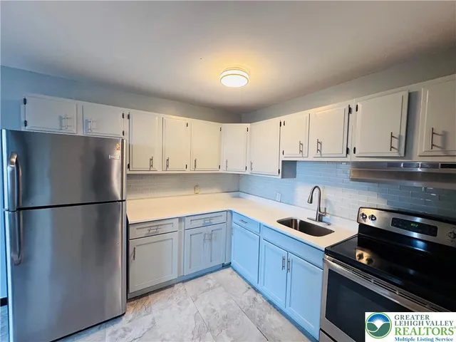 a kitchen with a refrigerator a stove a sink and cabinets