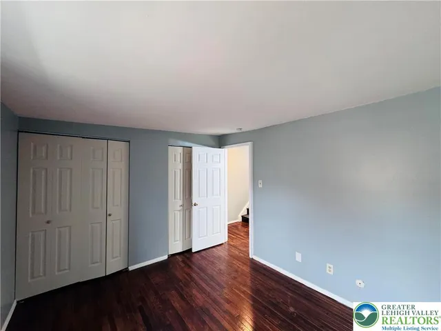 a view of an empty room with wooden floor and closet