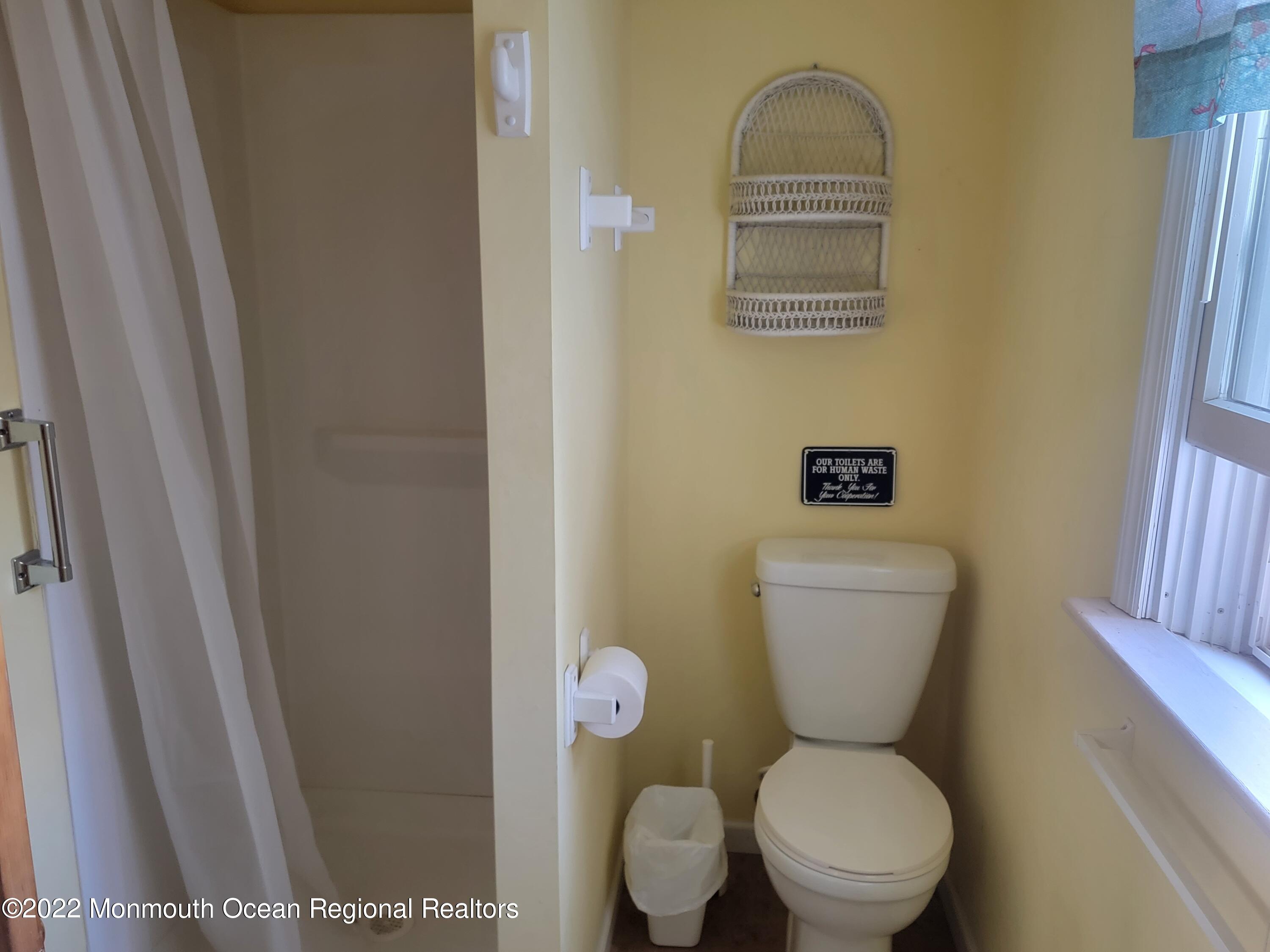 110 5th Avenue Seaside Park, NJ 08752 - Photo 13 of 25 a white toilet sitting next to a bathroom sink and a window