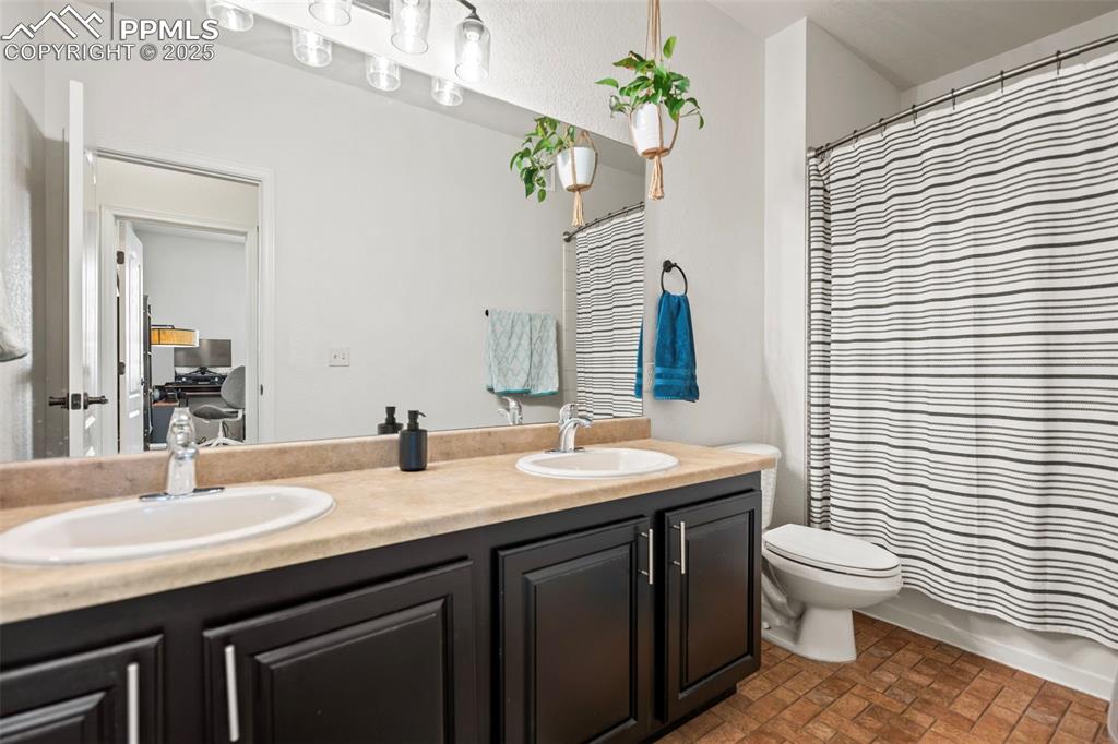 5378 Palomino Ranch Point, Unit 201 Colorado Springs, CO 80922 - Photo 10 of 15 a bathroom with a granite countertop sink a toilet and mirror