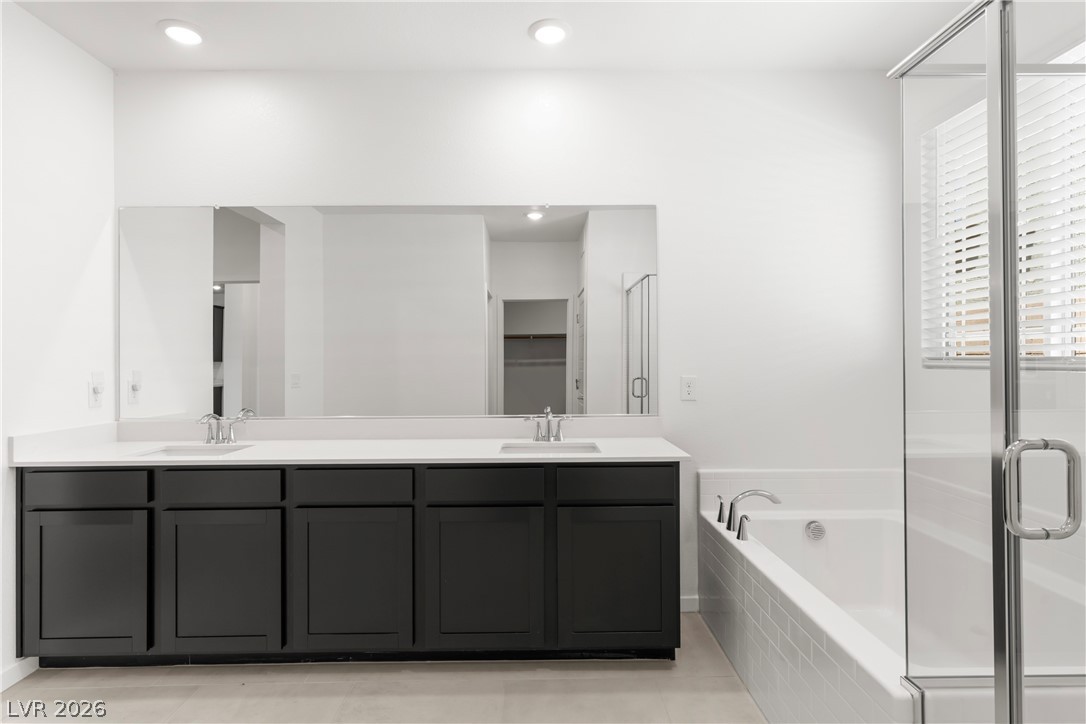 320 Isla Enclave Way Henderson, NV 89011 - Photo 14 of 49 Modern primary bathroom offers a dual vanity, a soaking tub, and a sleek glass shower enclosure.