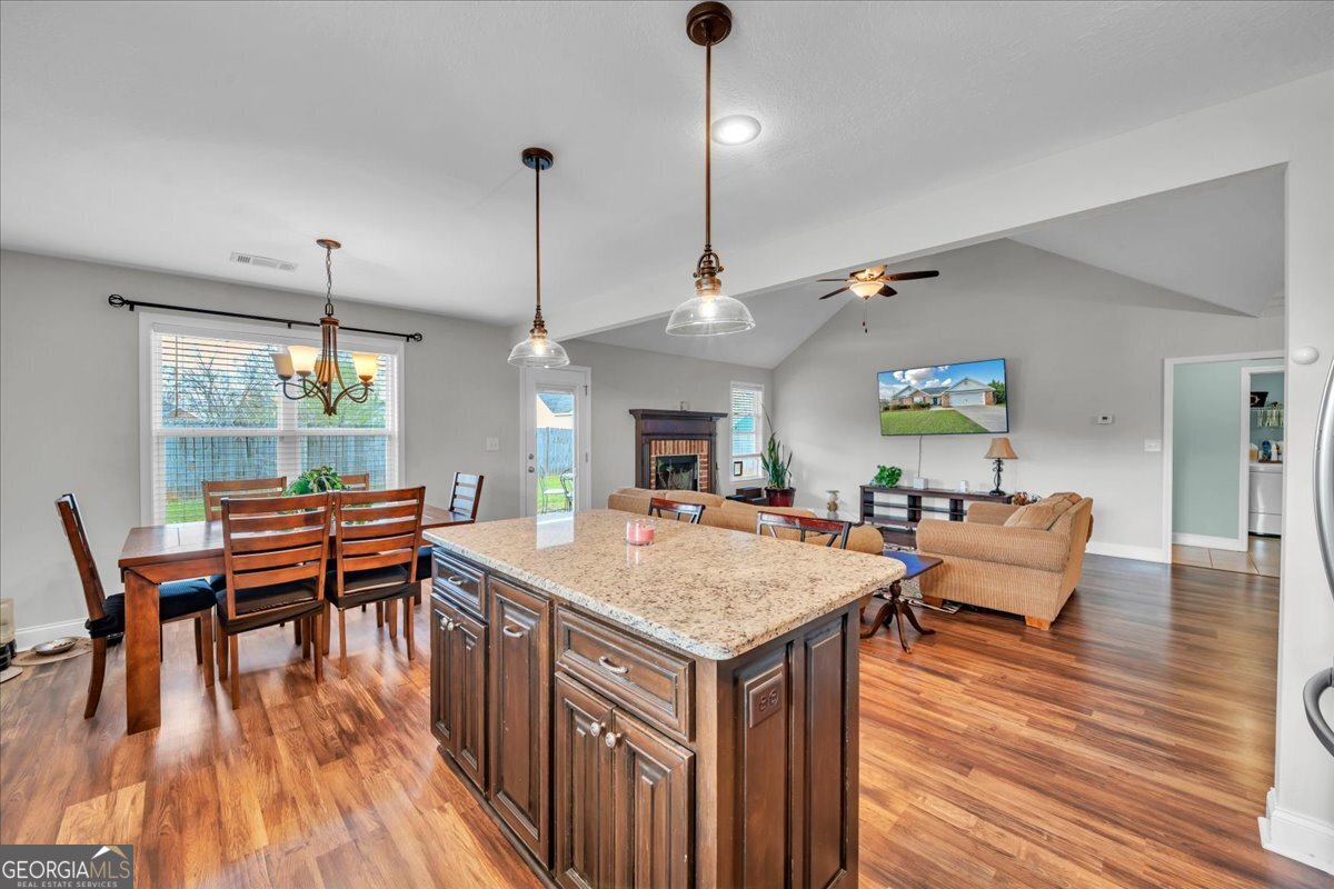 128 Gage Drive Perry, GA 31069 - Photo 13 of 38 a dining hall with stainless steel appliances granite countertop wooden floor a stove top oven a dining table and chairs with wooden floor