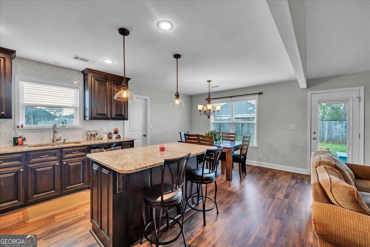 128 Gage Drive Perry, GA 31069 - Photo 7 of 38 a kitchen with stainless steel appliances granite countertop a stove a refrigerator a sink a dining table and chairs with wooden floor