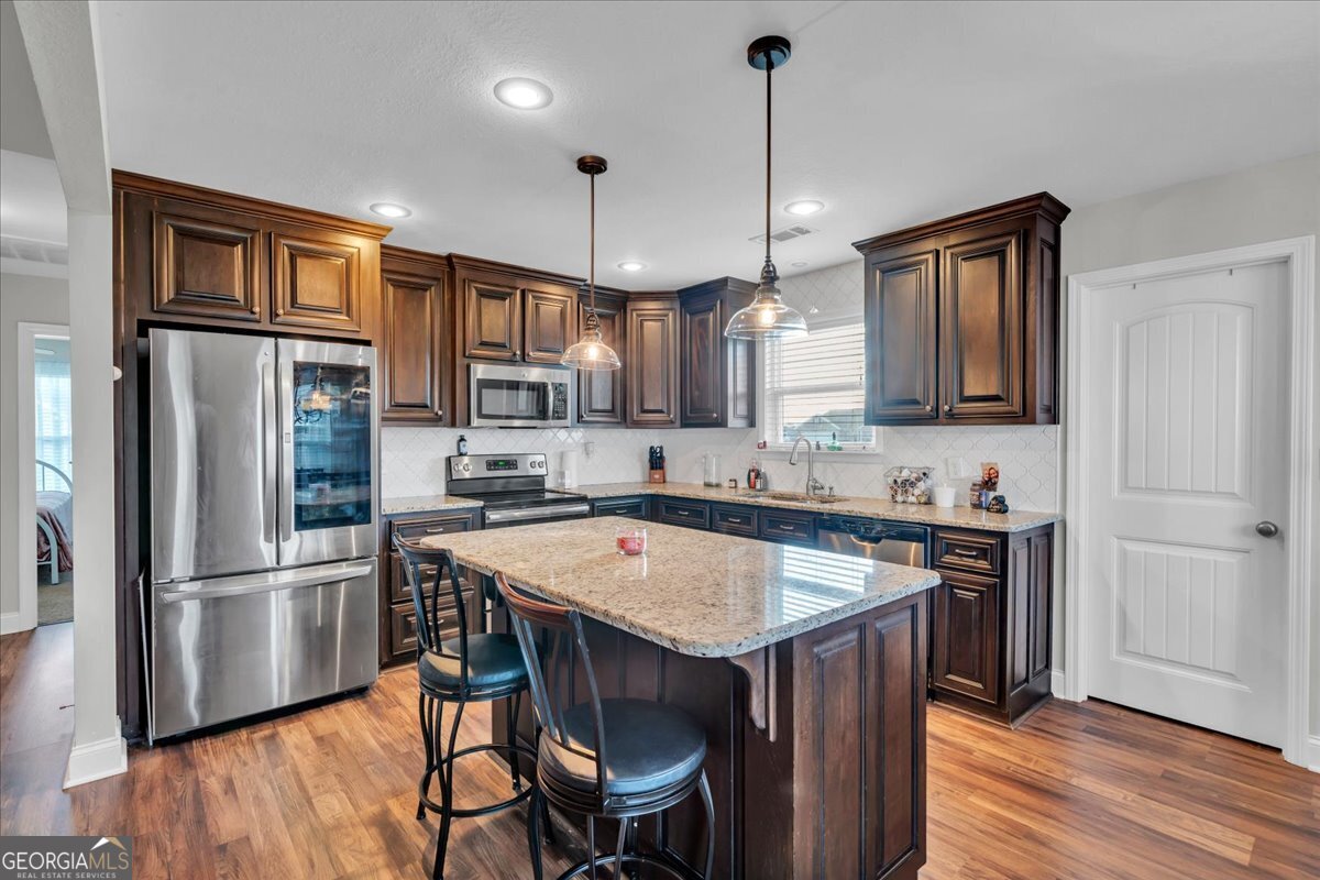128 Gage Drive Perry, GA 31069 - Photo 8 of 38 a kitchen with stainless steel appliances granite countertop a refrigerator a sink dishwasher a stove and white countertops with wooden floor