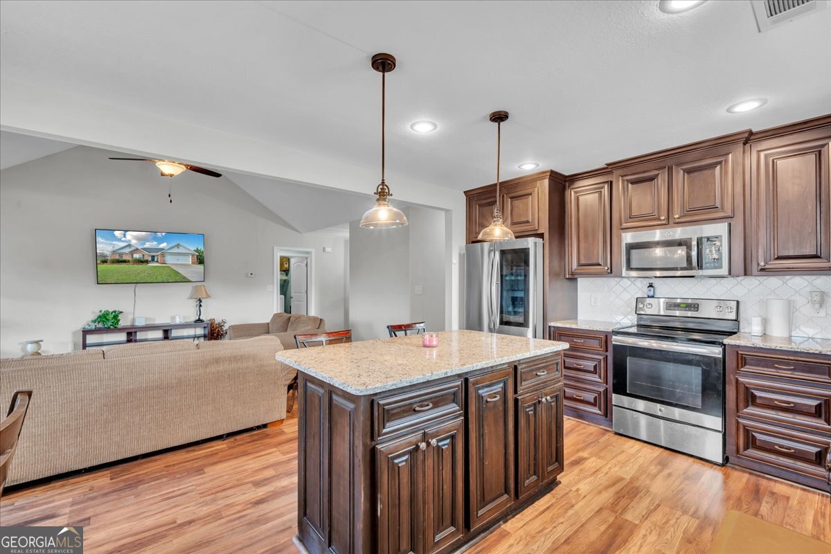 128 Gage Drive Perry, GA 31069 - Photo 9 of 38 a large kitchen with stainless steel appliances a stove a sink dishwasher a oven and a dining table with wooden floor