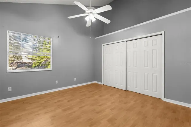 an empty room with a chandelier fan and windows