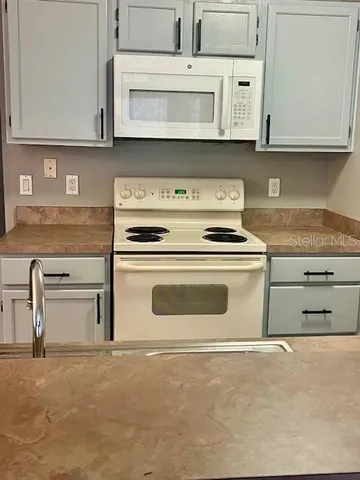 a kitchen with granite countertop white cabinets and a stove