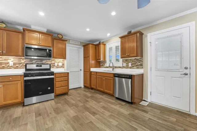 a kitchen with stainless steel appliances kitchen island granite countertop a stove top oven a sink and a refrigerator