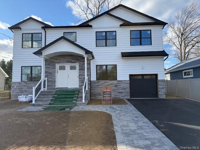 View of front of house featuring stone siding, a garage, and driveway