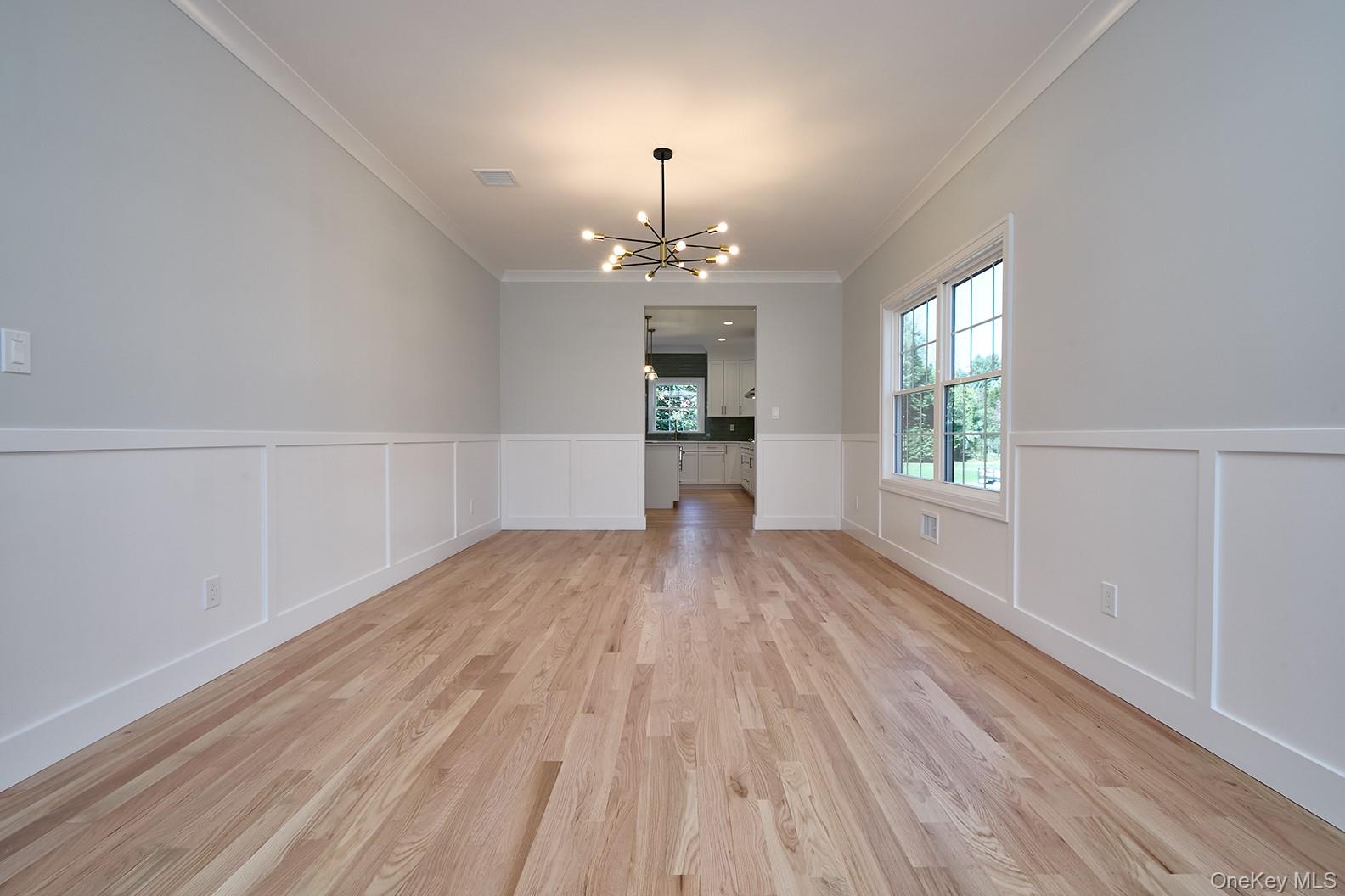 1480 Adam Place Wantagh, NY 11793 - Photo 3 of 22 Unfurnished dining area with a chandelier, wainscoting, a decorative wall, ornamental molding, and light wood-type flooring