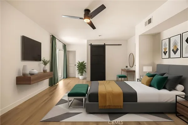 a bedroom with a bed a couch and a flat screen tv