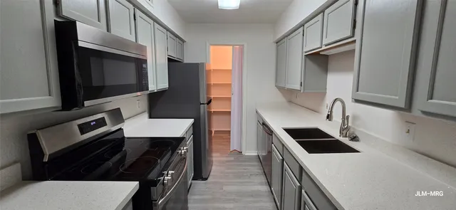 a kitchen with stainless steel appliances a sink a stove a microwave and a refrigerator