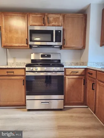 a kitchen with granite countertop a stove top oven microwave and cabinets