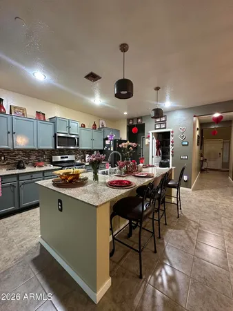 a kitchen with stainless steel appliances kitchen island granite countertop a sink a stove a dining table and chairs