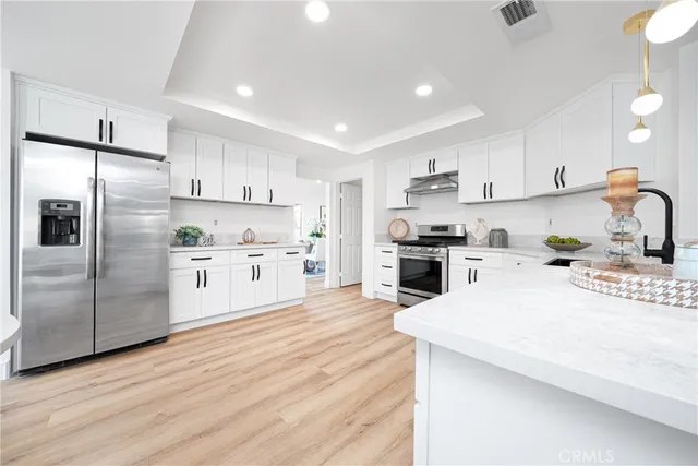 a kitchen with stainless steel appliances kitchen island a refrigerator sink and cabinets