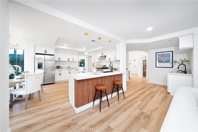 a living room with stainless steel appliances kitchen island granite countertop furniture and a wooden floor
