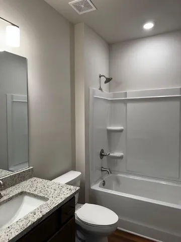 a bathroom with a granite countertop bathtub sink vanity mirror and toilet