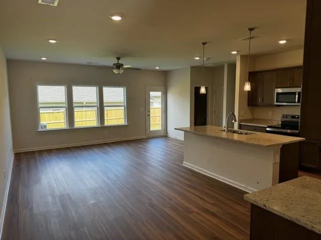 a view of a kitchen with kitchen island a sink wooden floor and a refrigerator