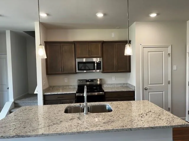a kitchen with stainless steel appliances kitchen island granite countertop a refrigerator and a sink