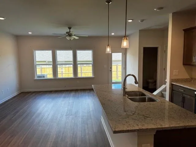 a kitchen with kitchen island granite countertop a stove a sink a refrigerator and wooden floor