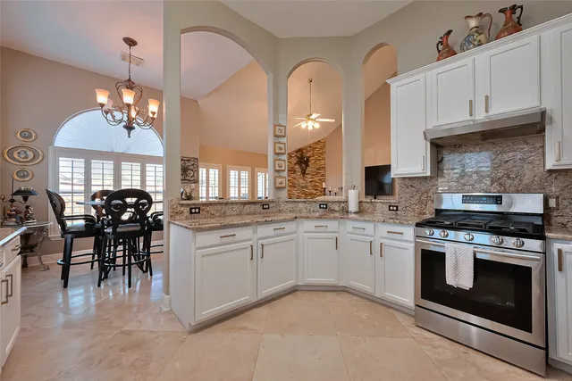 a kitchen with stainless steel appliances granite countertop a stove a sink a dining table and chairs with wooden floor