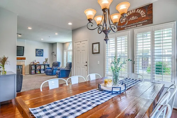a kitchen with stainless steel appliances granite countertop a refrigerator a stove a sink a dining table and chairs with wooden floor