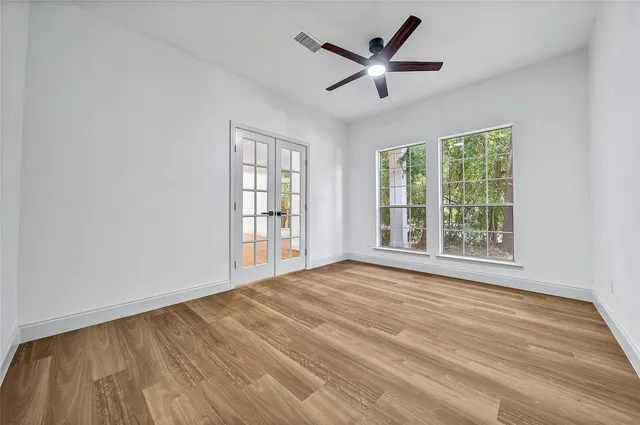 a view of empty room with wooden floor and fan