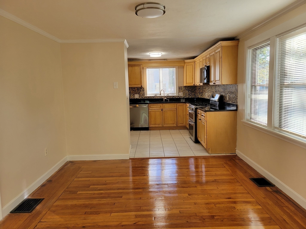 31 Avalon Avenue, Unit 1 Quincy, MA 02169 - Photo 4 of 10 a large white kitchen with wooden floor and a window