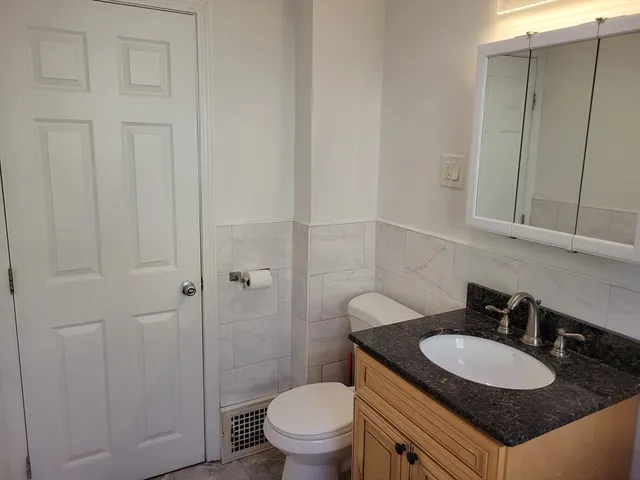 a bathroom with a granite countertop sink a toilet and a mirror