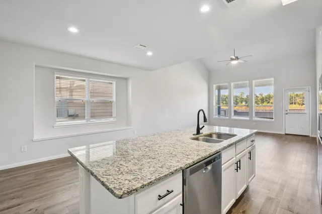 a kitchen with granite countertop kitchen island a sink stove and wooden floor
