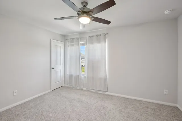 an empty room with a ceiling fan and carpet