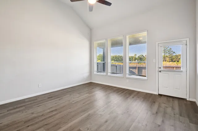 an empty room with wooden floor and windows