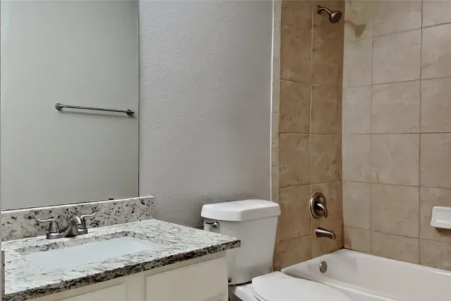 a bathroom with a granite countertop sink a toilet and shower