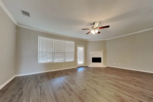 an empty room with wooden floor and a ceiling fan